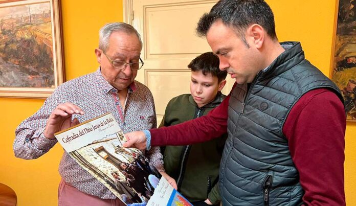 Alejandro Villahoz (centro) entre el mayordomo perpetuo de la cofradía y el alcalde de la villa observando el calendario del Niño de la Bola.